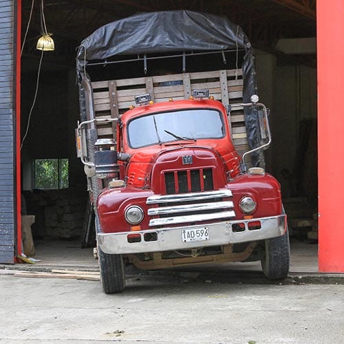 An old flat bed truck is loaded with green coffee at a Colombian coffee warehouse.