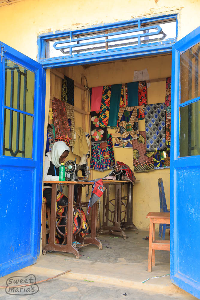 Many times the washing stations are located by small villages of 10-20 shops that offer various goods and services. Next to Karambi station, sewing African wax cloth into garments.
