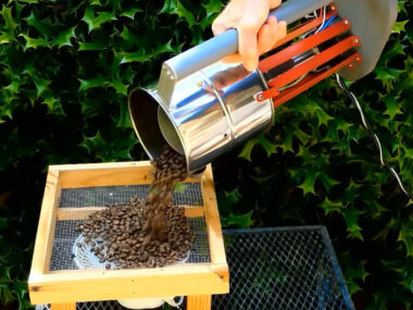 A screenshot of Larry Cotton's EZ Wobble Disk Coffee Roaster in action. The handle encompasses the whole roaster, which tips over to drop the coffee in a metal sieve.
