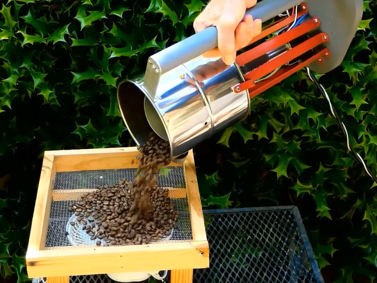 A screenshot of Larry Cotton's EZ Wobble Disk Home Coffee Roaster in action. The handle encompasses the whole roaster, which tips over to drop the coffee in a metal sieve.