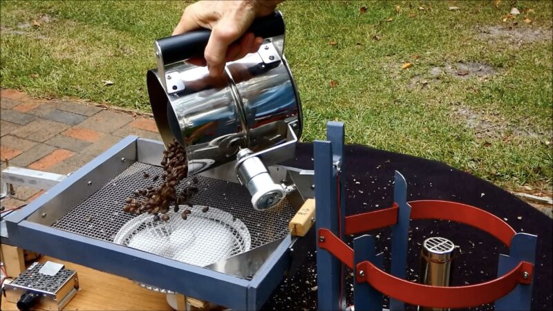 A screenshot of Larry Cotton's Wobble Disk Home Coffee Roaster in action. The handle encompasses the roasting chamber, which tips over to drop the coffee in a metal mesh bed.