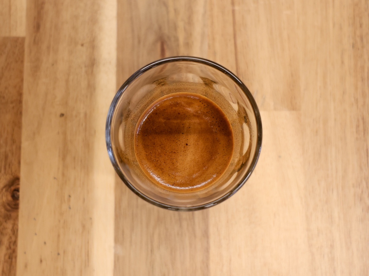 The crema of an espresso shot of Sweet Maria's Liquid Amber Blend from a birds-eye view. The espresso is in a small glass.