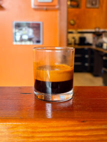 An espresso shot glass half-full with a shot of Silvertone (roasted to City+). There's a lot of crema at the top.