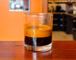 An espresso shot glass half-full with a shot of Silvertone (roasted to City+). There's a lot of crema at the top.