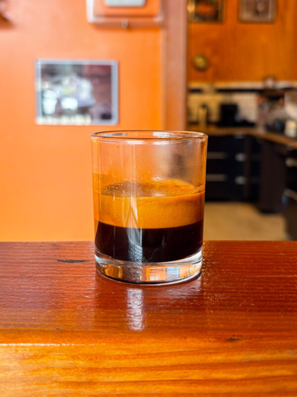 An espresso shot glass half-full with a shot of Silvertone (roasted to City+). There's a lot of crema at the top.